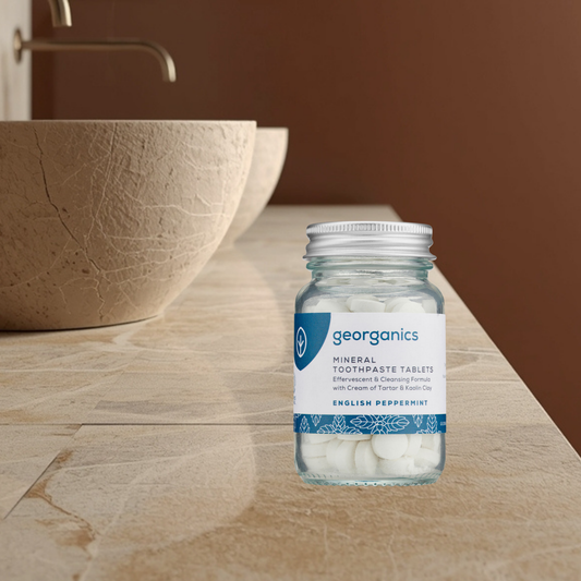 Bottle of georganics mineral toothpaste tablets peppermint on a bathroom counter.