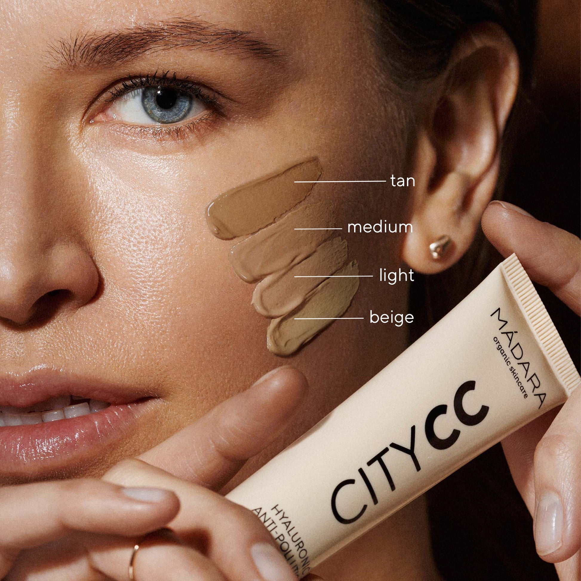 Woman applying Madara City CC cream with color swatches on her face