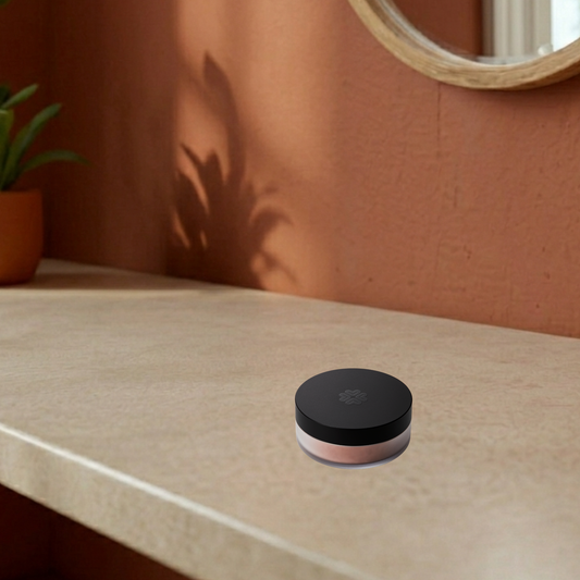 Lily Lolo mineral blush on a beige surface with a plant and mirror in the background.
