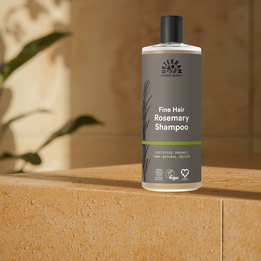 Bottle of Urtekram Rosemary Shampoo on a wooden surface with a blurred background
