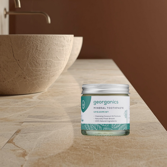 Georganics mineral toothpaste jar on a wooden surface with a brown wall background