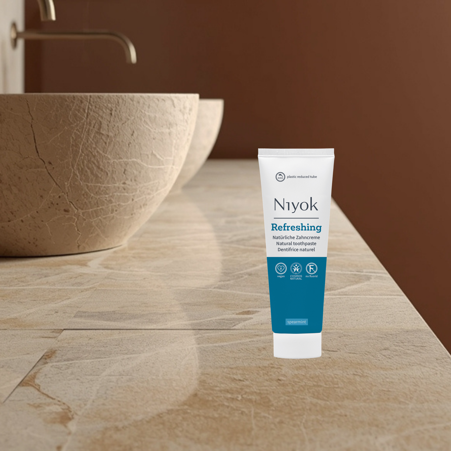 Niyok refreshing tube on a bathroom counter with a brown wall and sink in the background