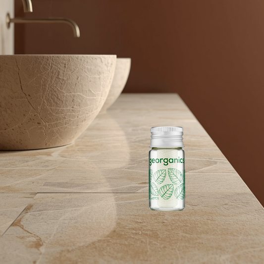 Georganics silk dental floss in a glass bottle on a wooden surface with a brown background