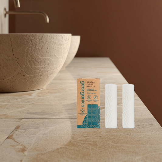 Two Georganics dental floss refills and their packaging on a bathroom counter.