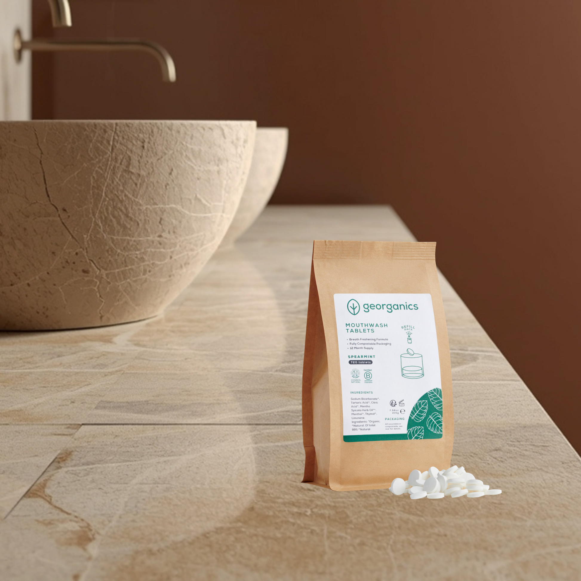 Georganics spearmint mouthwash tablets refill pouch on a stone surface with a brown bowl in the background