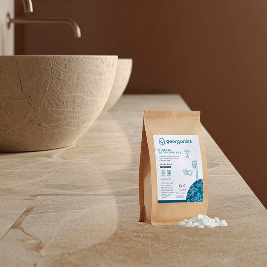 Georganics peppermint mineral toothpaste tablets refill pouch on a bathroom counter with a bowl in the background