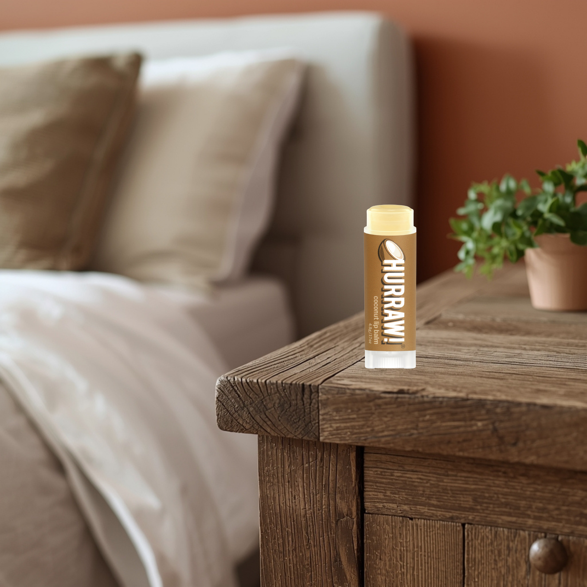 Hurraw coconut lip balm on a wooden nightstand with a blurred bedroom background