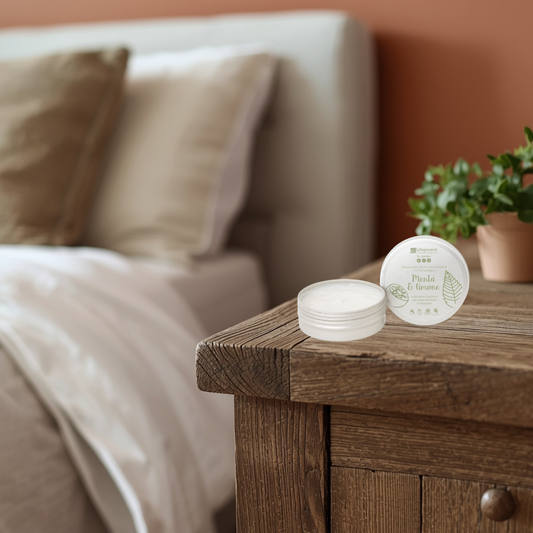 La Saponaria mint & lemon hand cream on a wooden nightstand with a bed and plant in the background