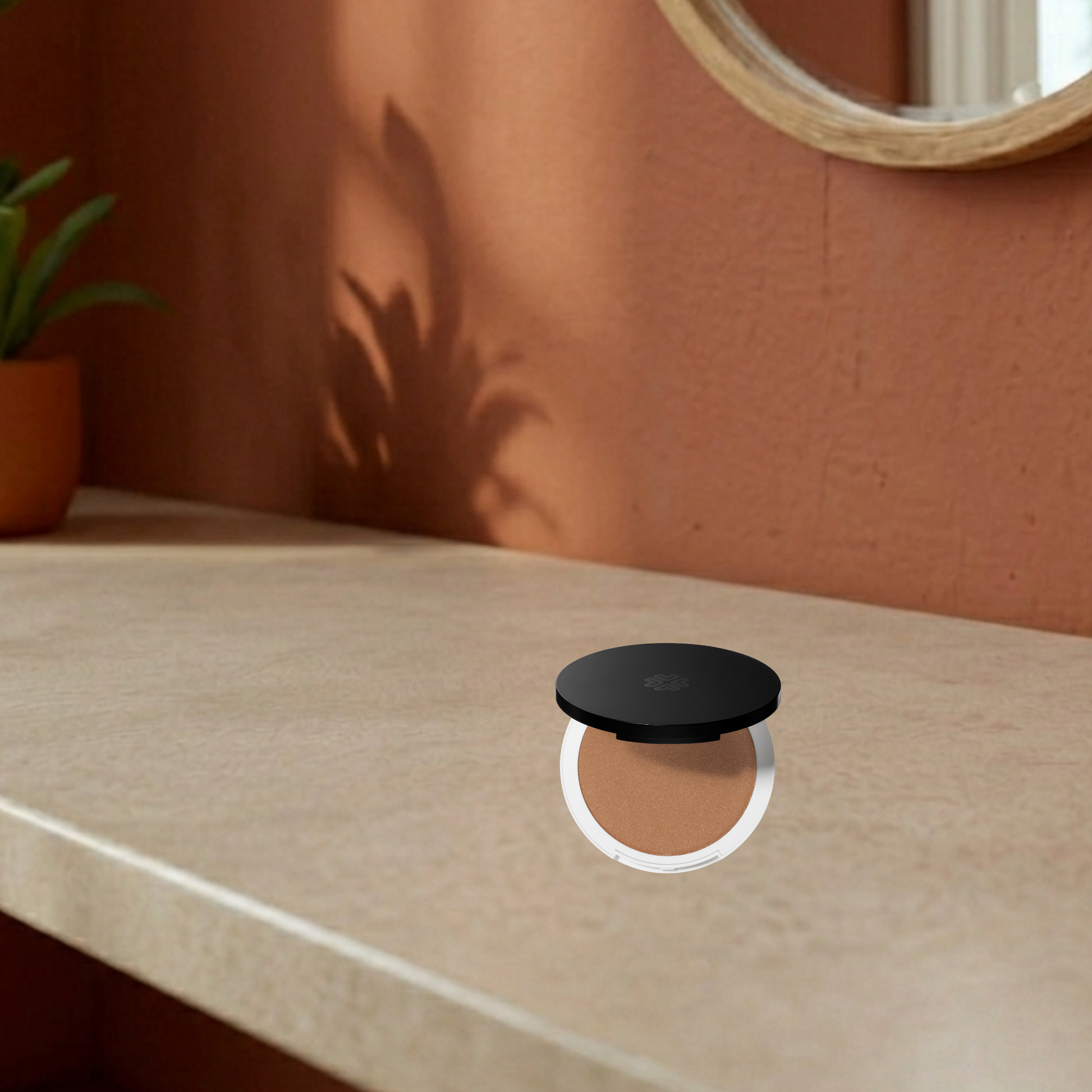 Black round pressed bronzer miami beach on a beige surface with a plant and mirror in the background