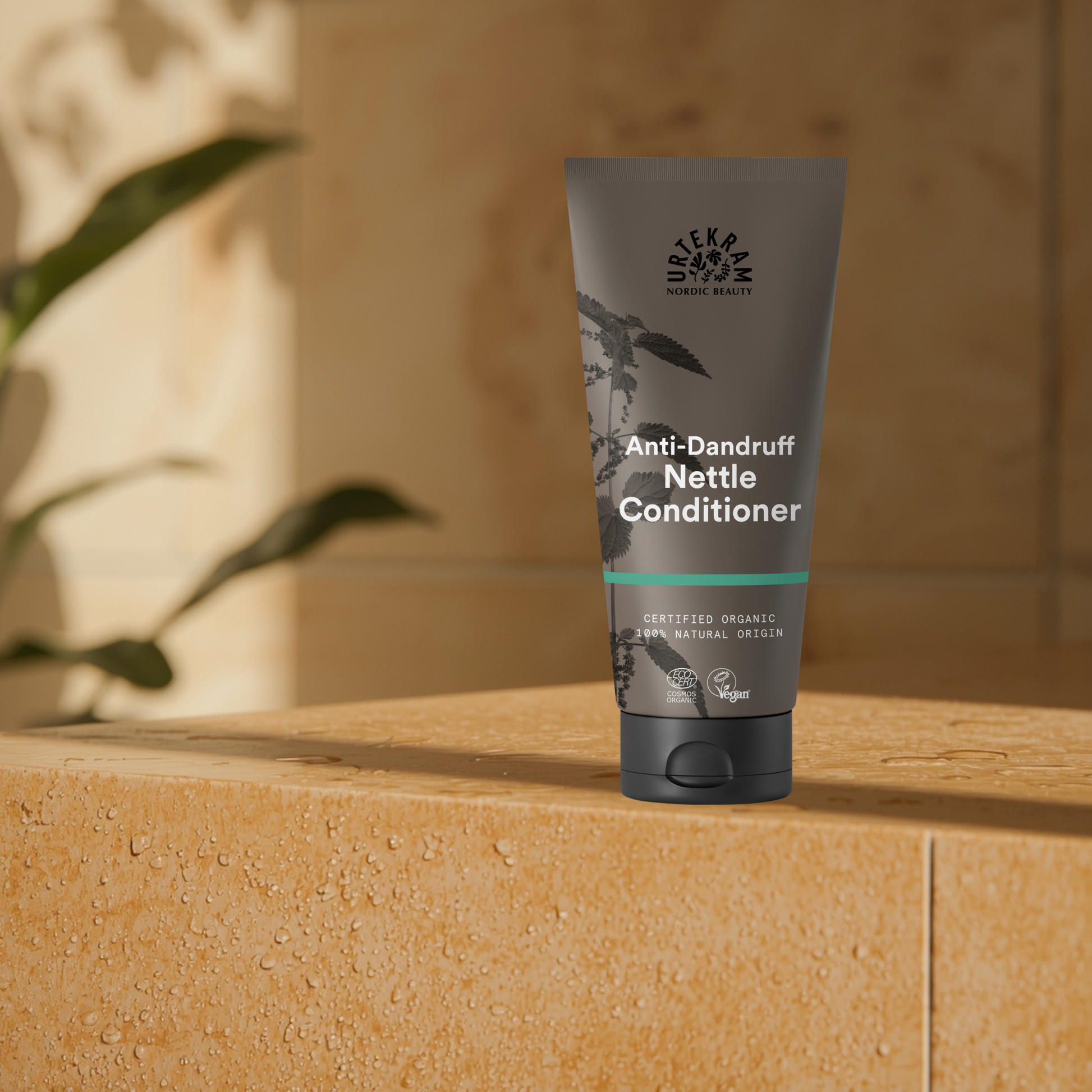 Anti-dandruff nettle conditioner tube on a wooden surface with a plant in the background