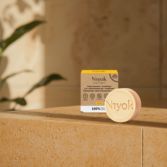 Niyok vitamina citrus shampoo and conditioner bar and packaging on a stone surface with a blurred background