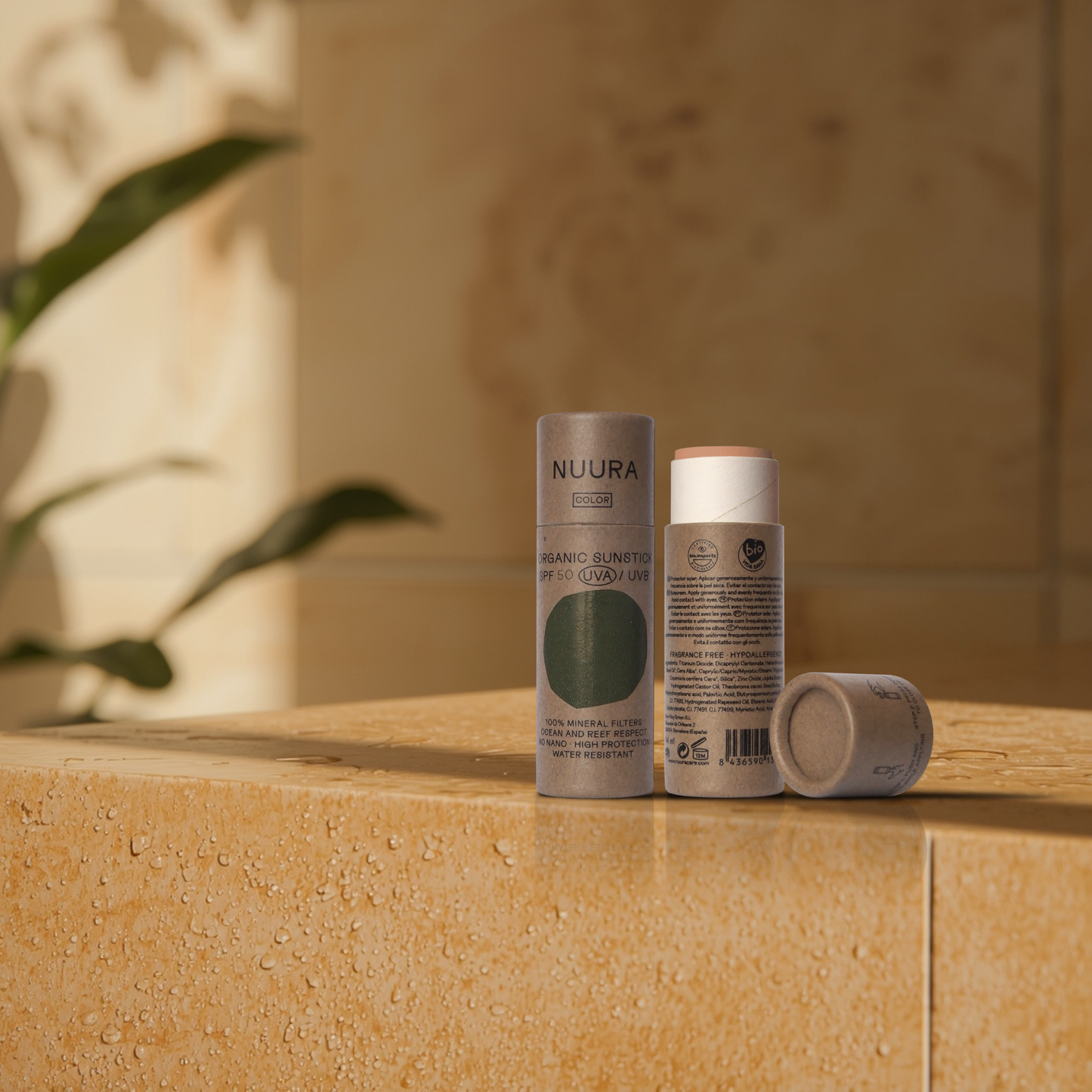 The NUURA sunscreen stick on a stone surface with a blurred natural background