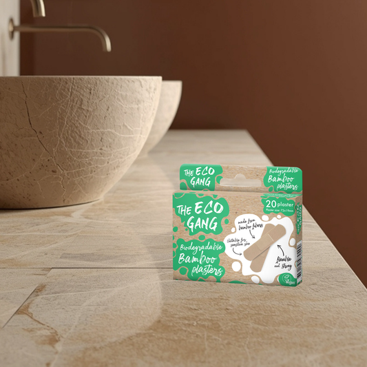 Box of 'The Eco Gang' bamboo plasters on a bathroom counter with a brown bowl and sink in the background.