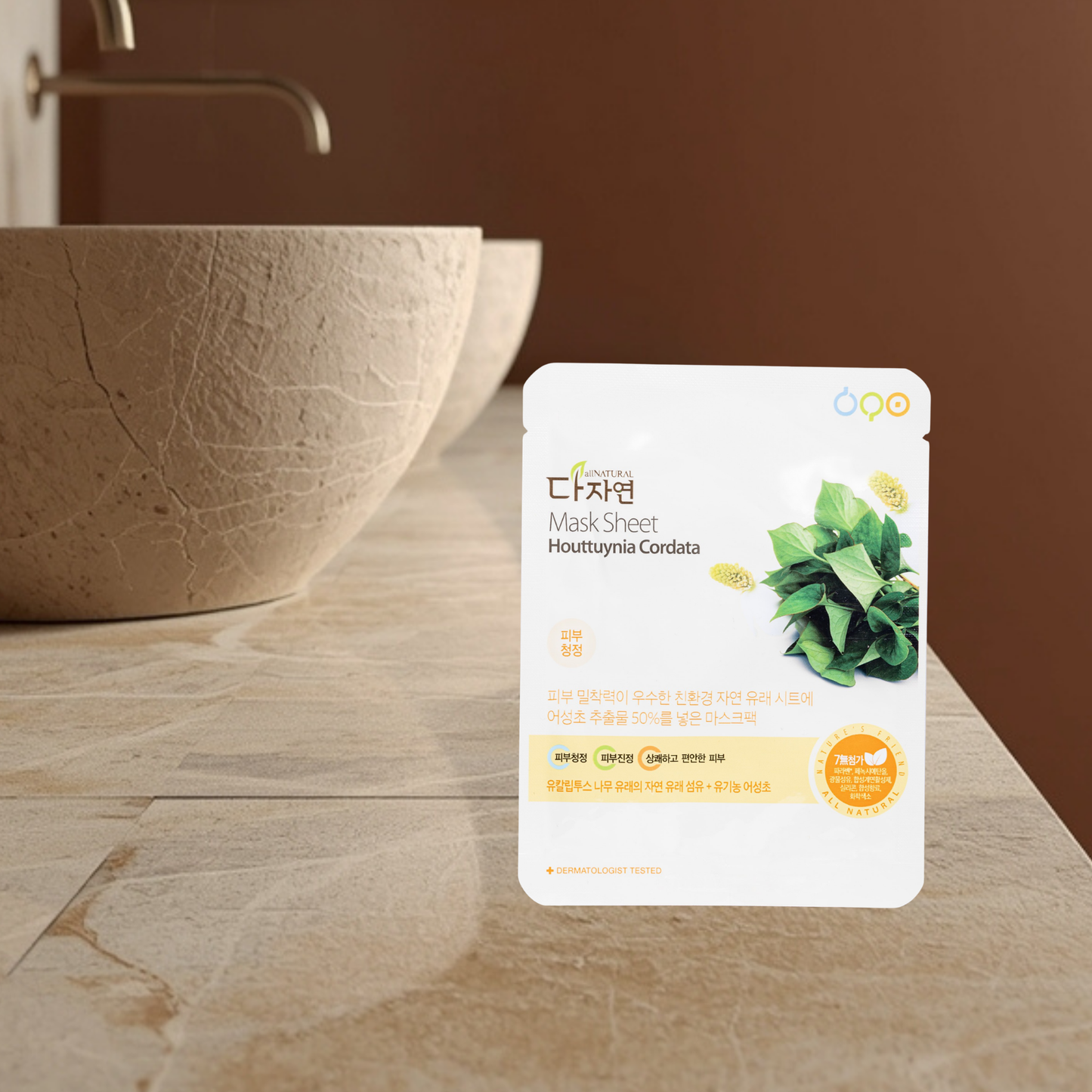 Mask sheet packaging of All Natural Houttuynia Cordata on a bathroom counter with a brown bowl and blurred background