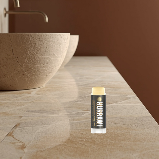 HURRRAW! sun lip balm on a bathroom counter with a sink in the background