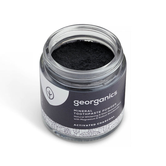 Jar of georganics activated charcoal mineral toothpaste powder with black powder inside on a white background
